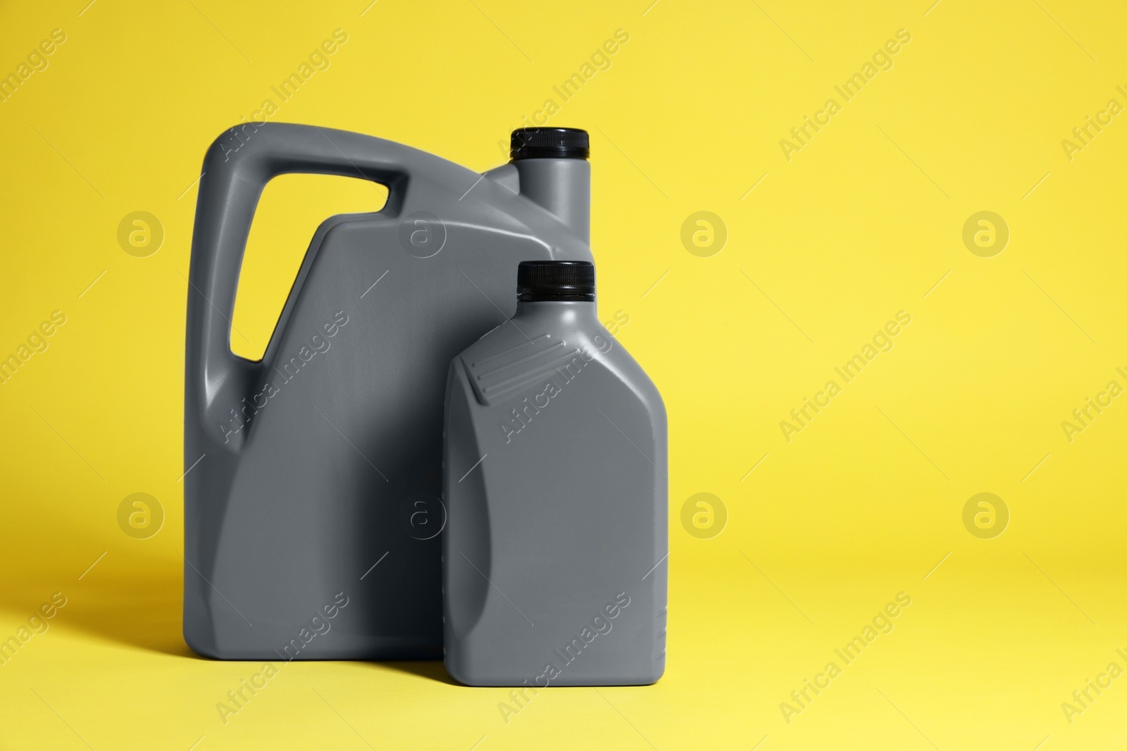 Photo of Two grey plastic canisters on yellow background, space for text