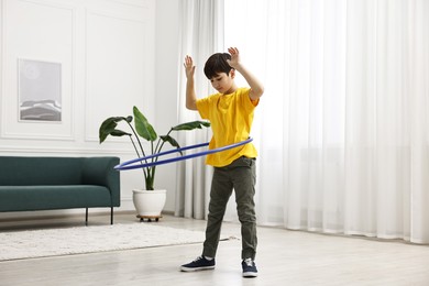 Photo of Boy exercising with hula hoop at home