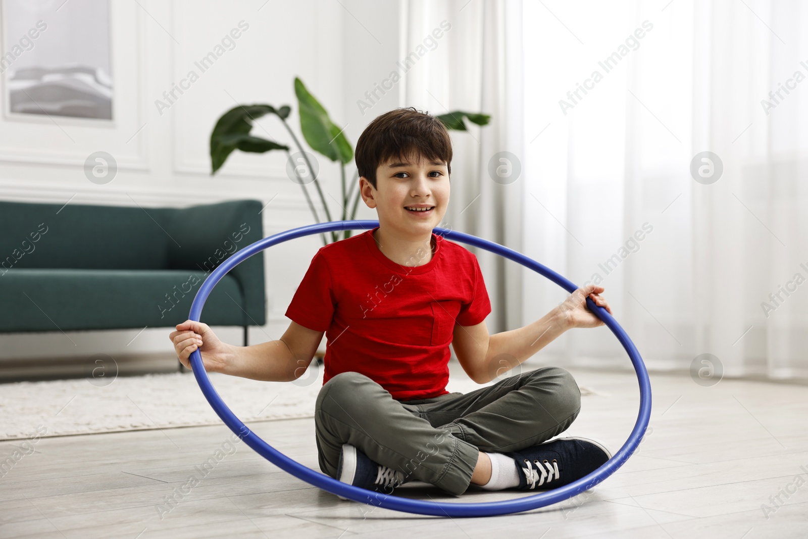 Photo of Smiling boy with hula hoop on floor at home