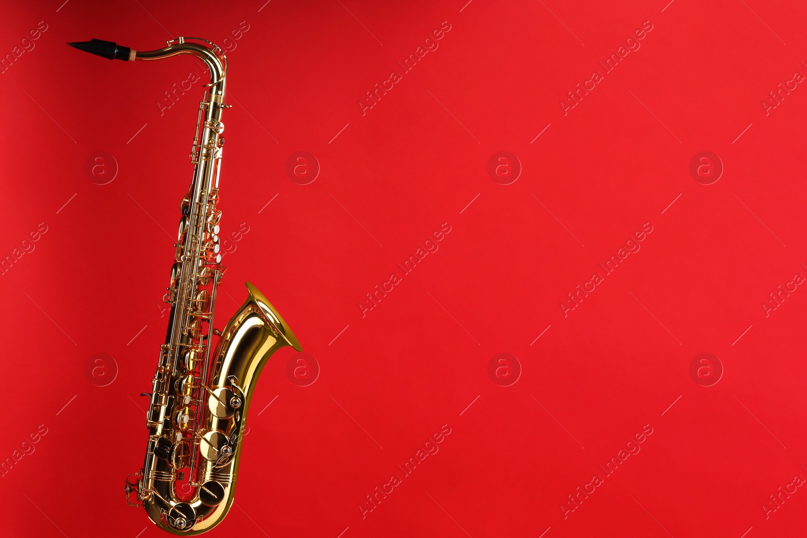 Photo of Jazz. One beautiful saxophone on red background, space for text