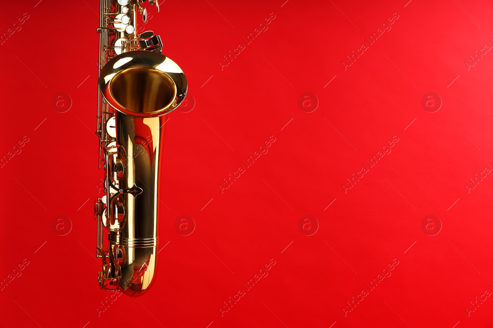 Photo of Jazz. One beautiful saxophone on red background, space for text