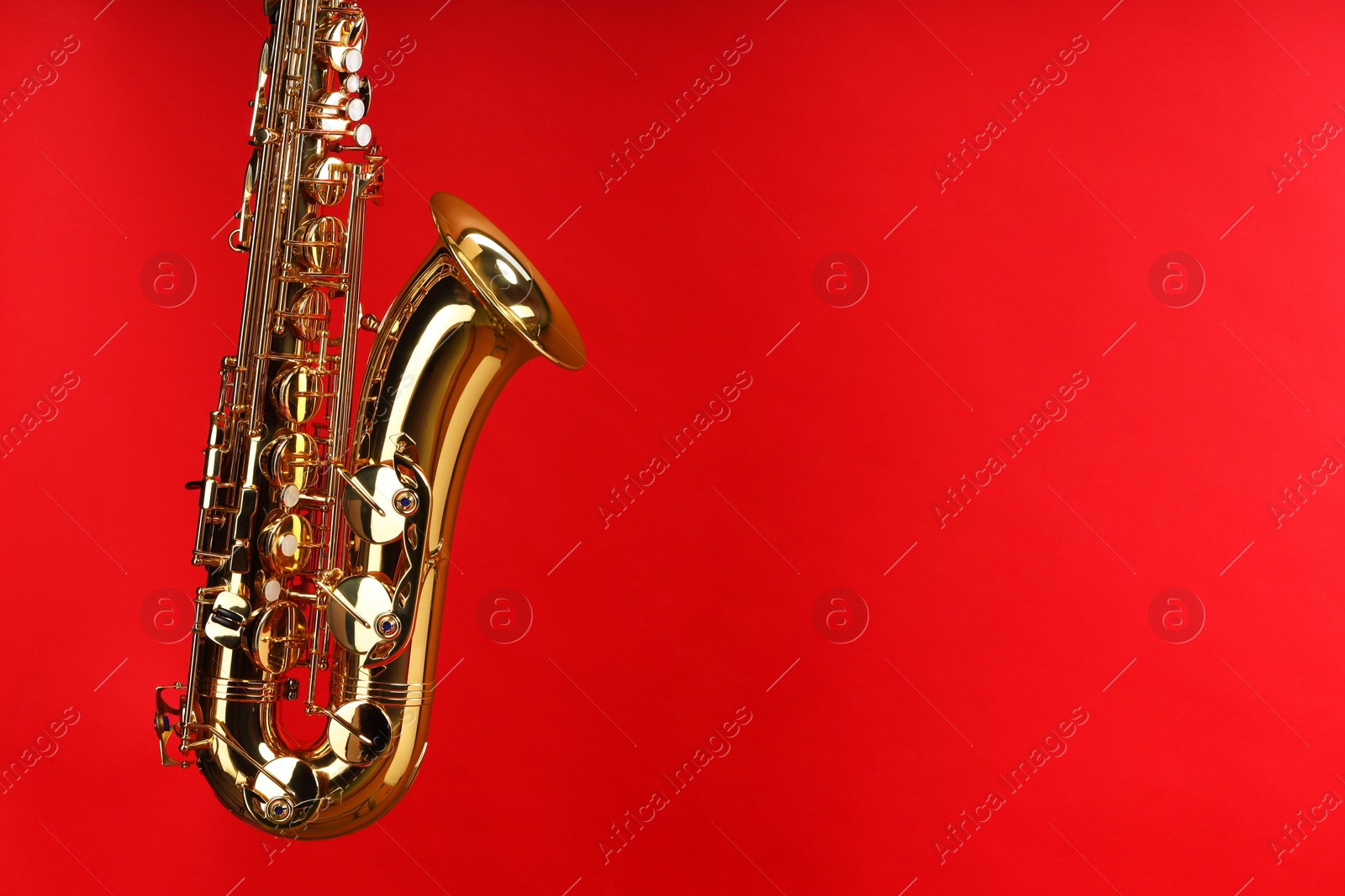 Photo of Jazz. One beautiful saxophone on red background, space for text