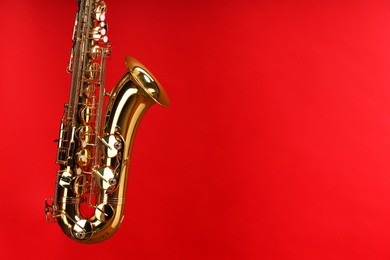 Photo of Jazz. One beautiful saxophone on red background, space for text