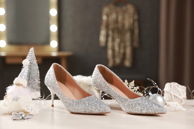 Elegant high heeled shoes and Christmas decor on white wooden table indoors