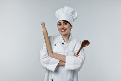 Photo of Professional chef with rolling pin and ladle on light grey background