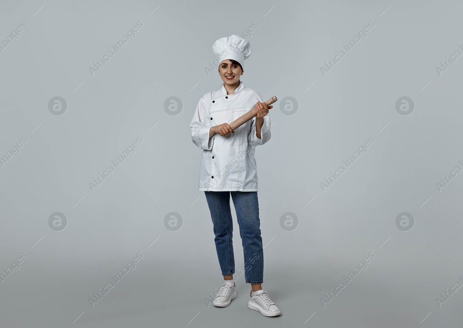 Photo of Professional chef with rolling pin on light grey background