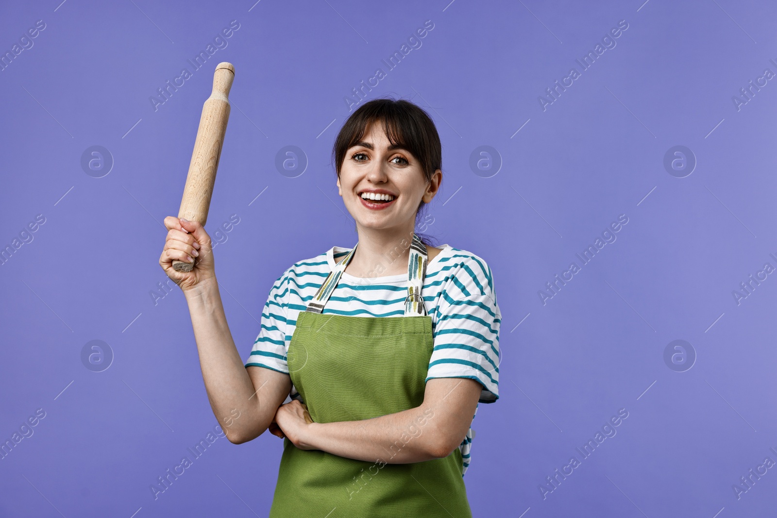 Photo of Happy woman with rolling pin on violet background