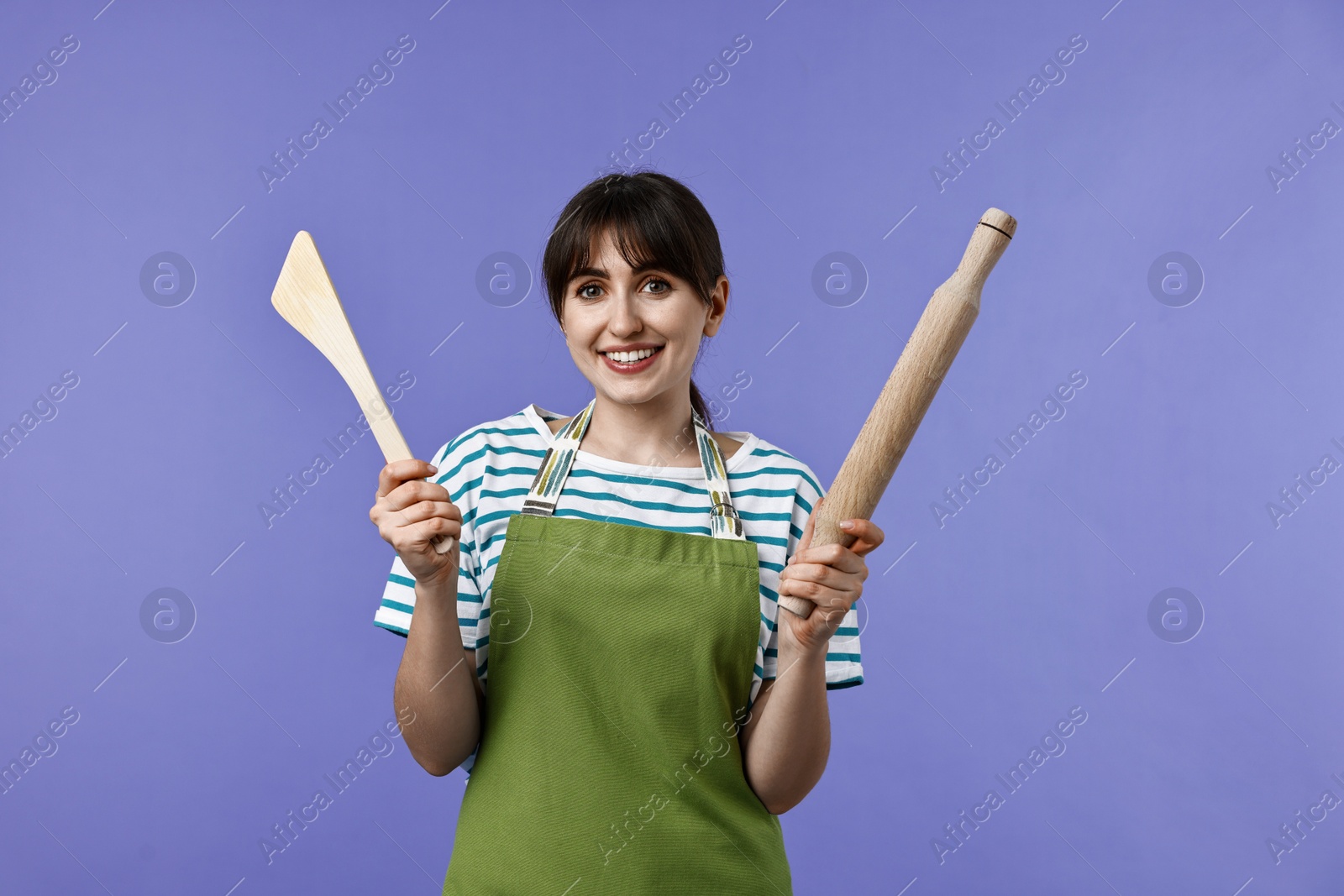 Photo of Woman with rolling pin and turner on violet background