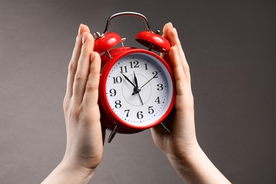 Photo of Woman with red alarm clock on grey background, closeup