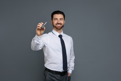 Cheerful salesman with car key on grey background