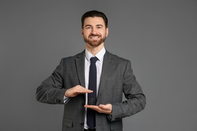 Photo of Cheerful salesman with car key on grey background