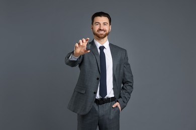 Cheerful salesman with car key on grey background