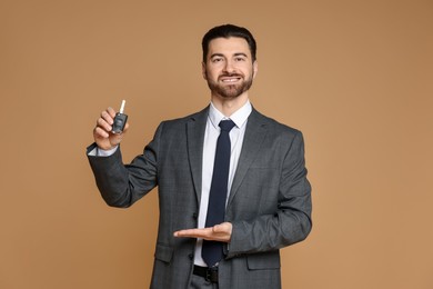 Photo of Cheerful salesman showing car key on beige background