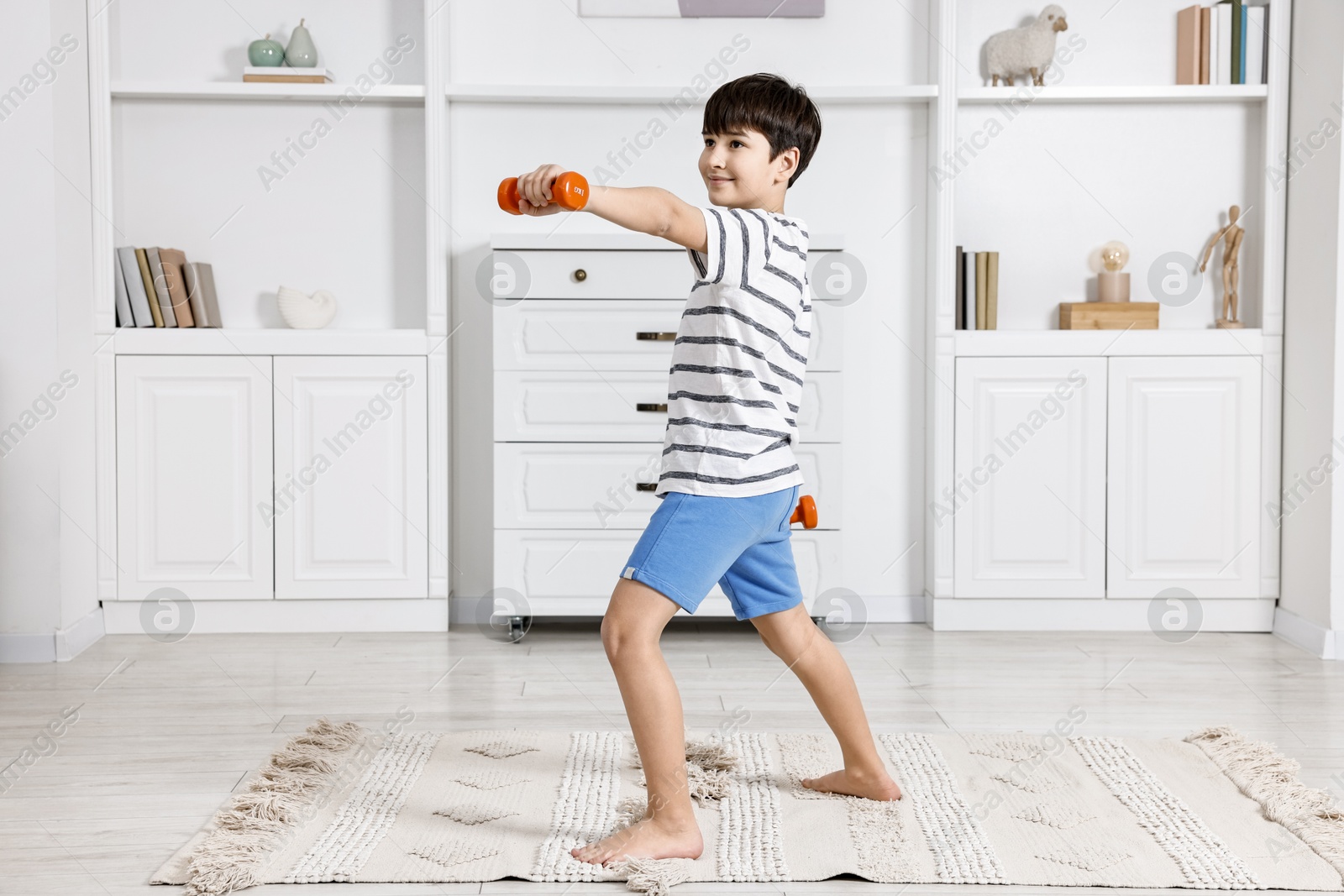 Photo of Little boy exercising with dumbbells at home. Morning routine