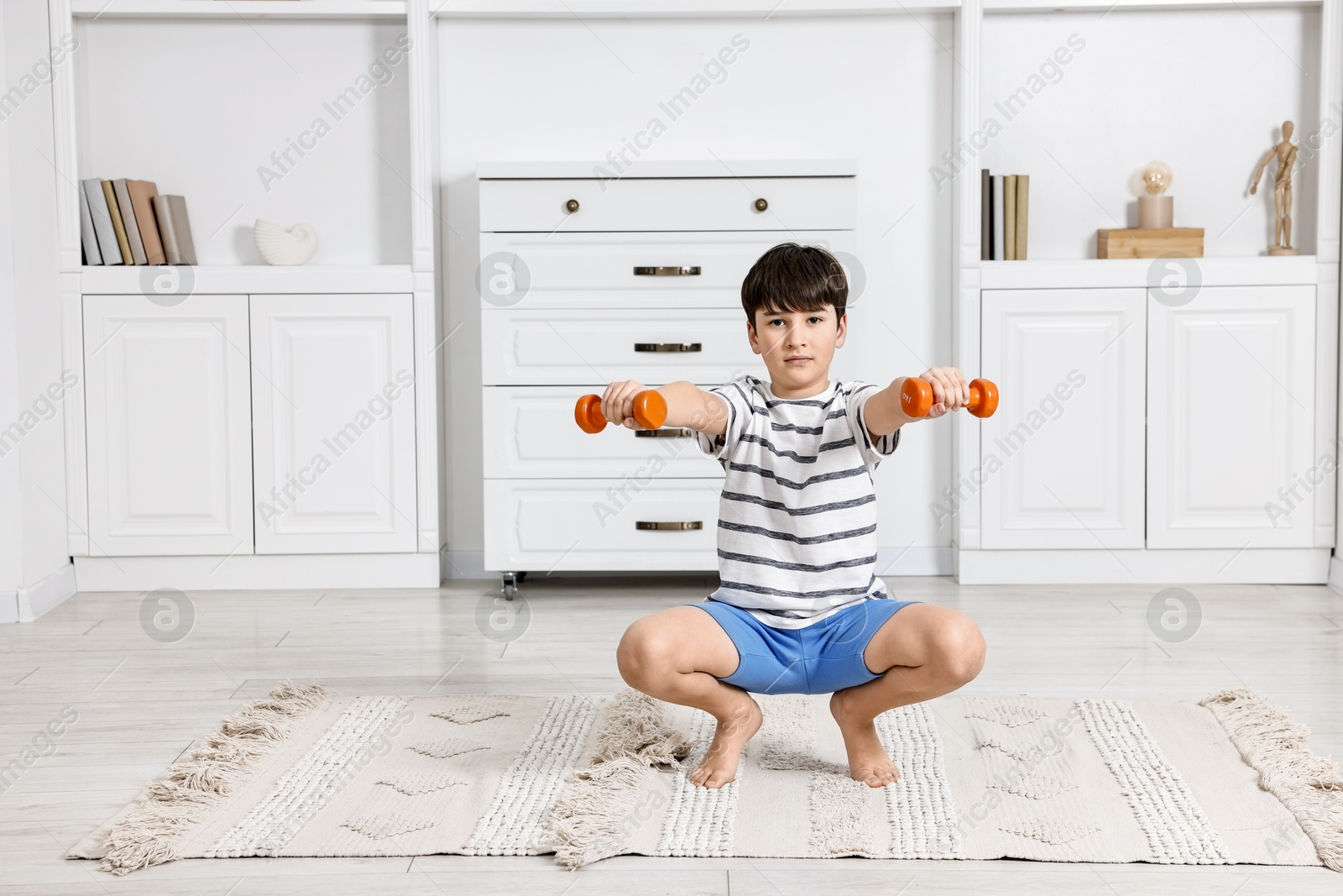 Photo of Little boy exercising with dumbbells at home. Morning routine