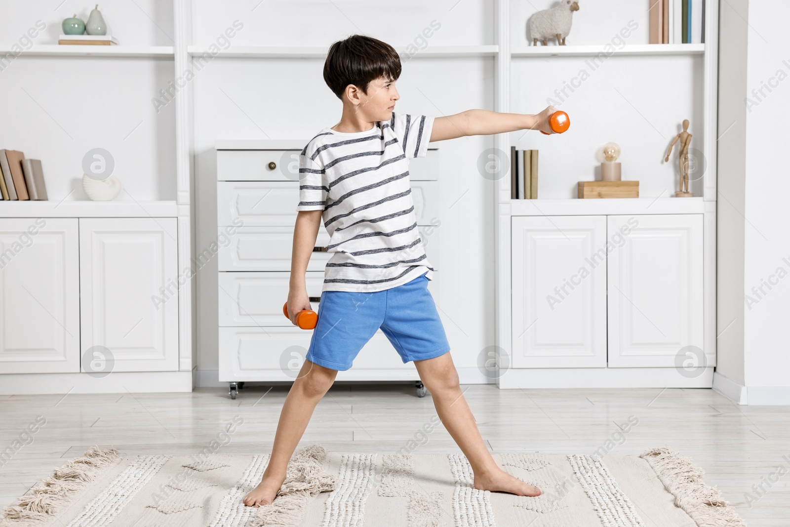 Photo of Little boy exercising with dumbbells at home. Morning routine