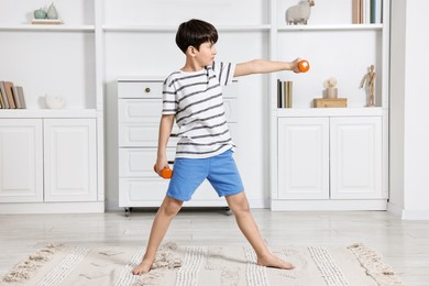 Little boy exercising with dumbbells at home. Morning routine