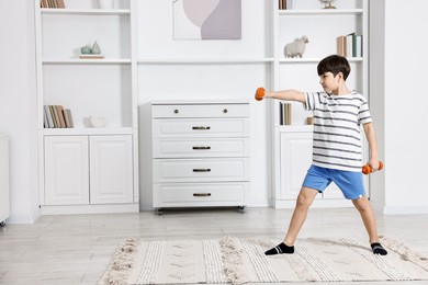 Little boy exercising with dumbbells at home. Morning routine