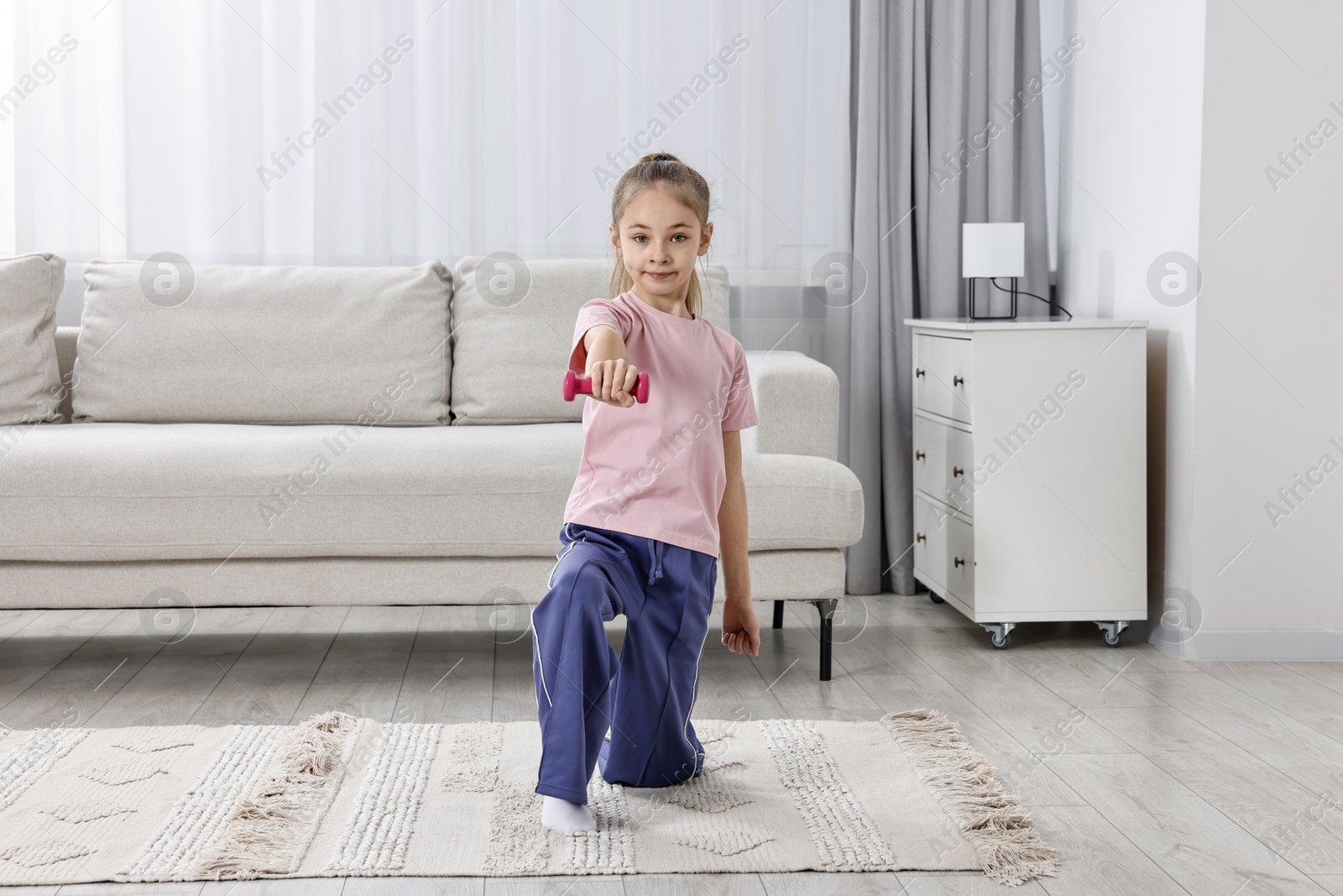 Photo of Little girl exercising with dumbbells at home. Morning routine