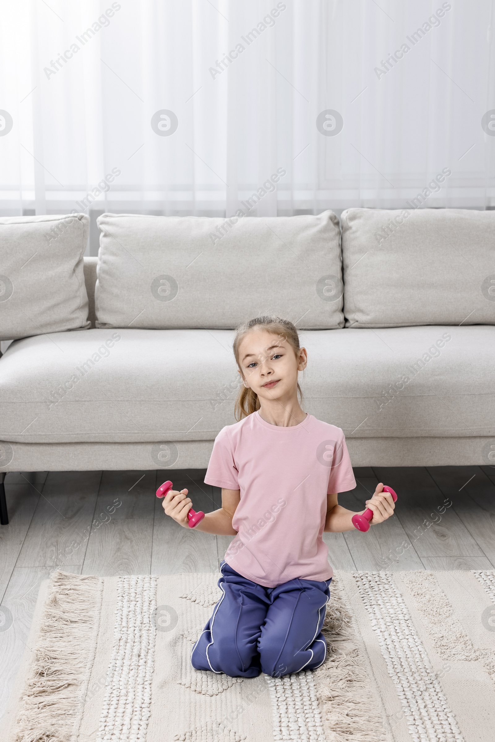 Photo of Little girl exercising with dumbbells at home. Morning routine