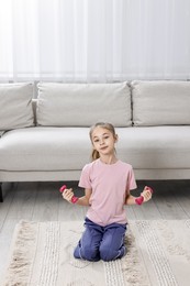 Photo of Little girl exercising with dumbbells at home. Morning routine