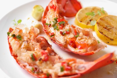 Photo of Delicious lobster tails with lemon, microgreens and green onion on white plate, closeup