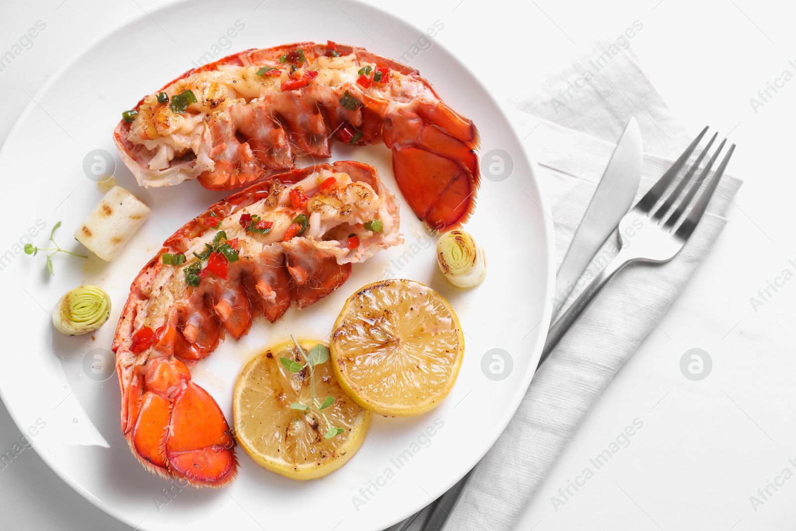 Photo of Delicious lobster tails with lemon, microgreens and green onion on white table, top view