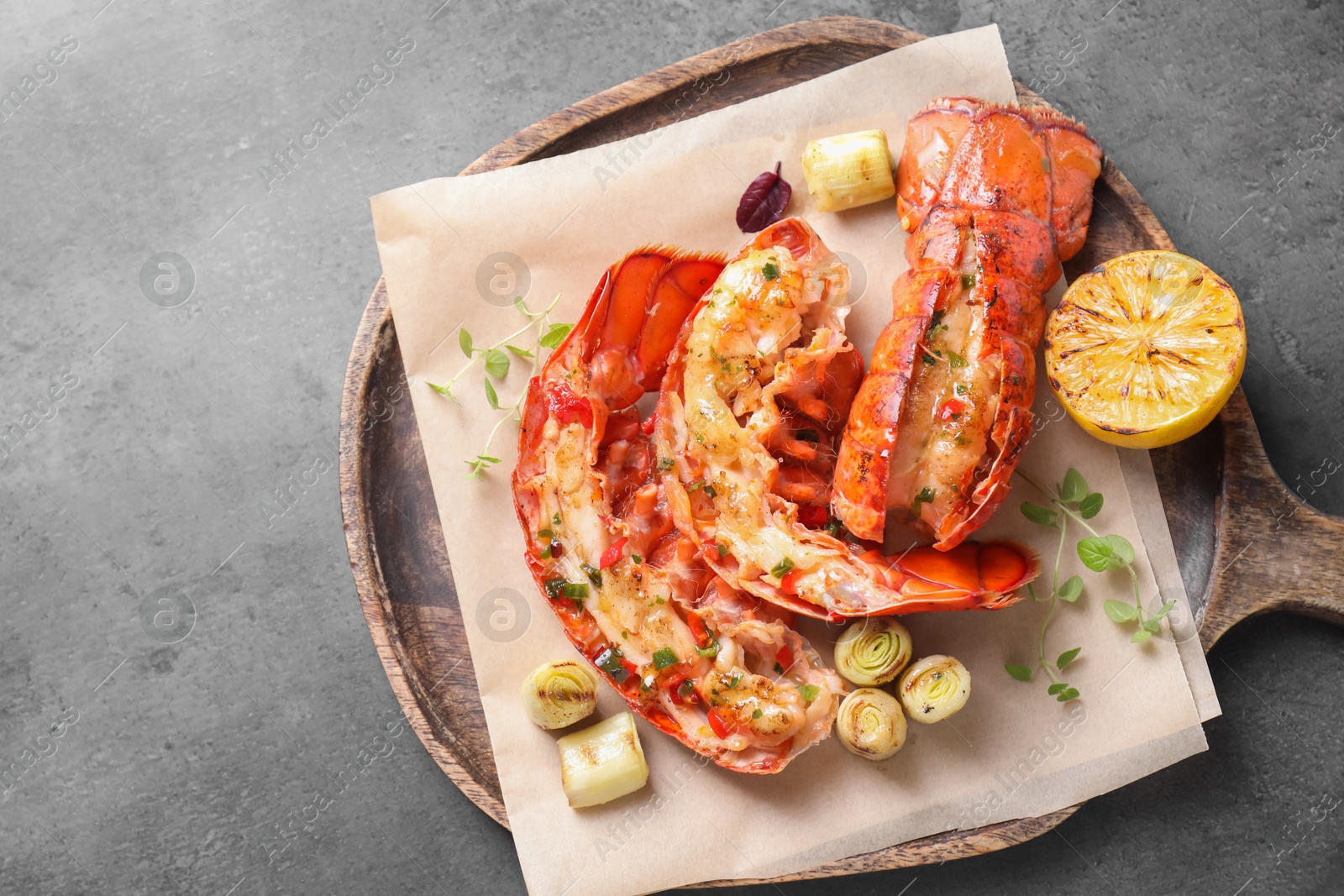 Photo of Delicious lobster tails with lemon, microgreens and green onion on grey textured table, top view. Space for text