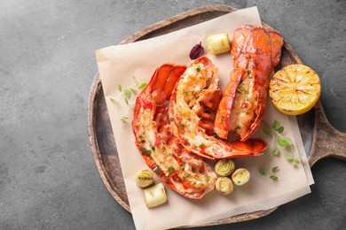 Delicious lobster tails with lemon, microgreens and green onion on grey textured table, top view. Space for text