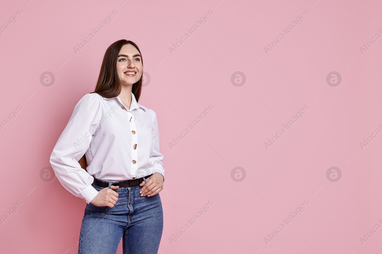 Photo of Smiling woman in stylish jeans on pink background. Space for text