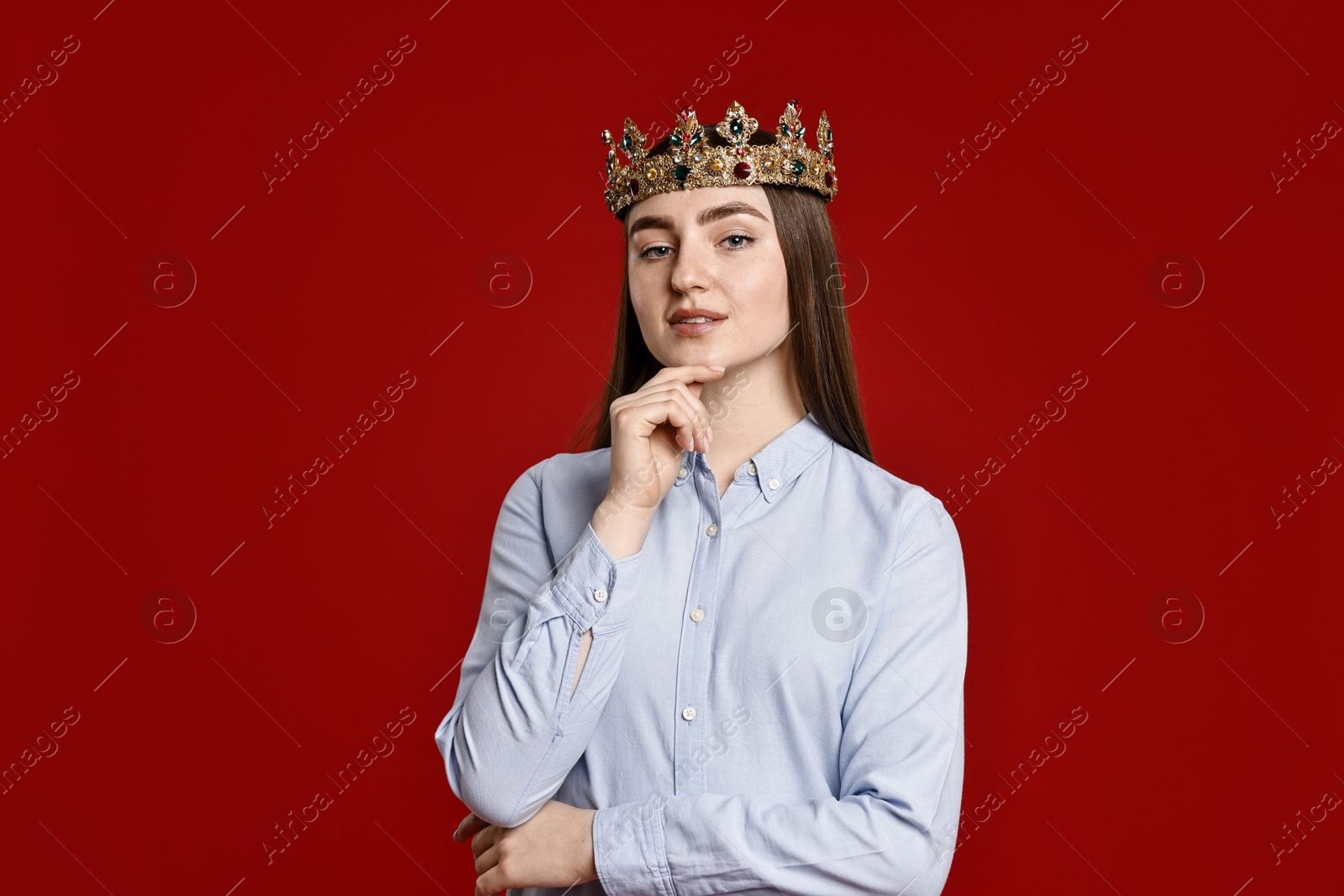 Photo of Woman in elegant crown on dark red background