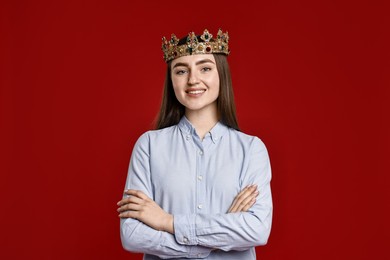 Photo of Smiling woman in elegant crown on dark red background