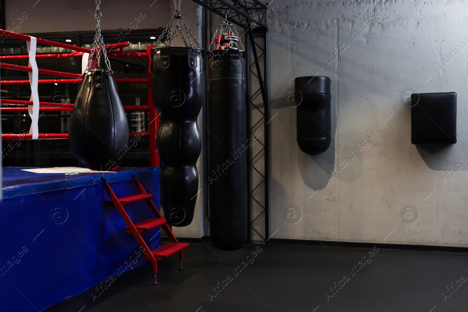 Photo of Punching bags and boxing ring in training center