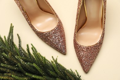 Photo of Shiny high heeled shoes and decorative Christmas tree on beige background, flat lay