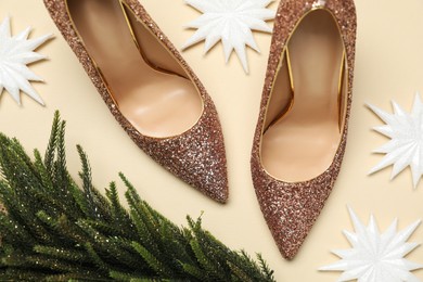 Photo of Shiny high heeled shoes, decorative Christmas tree and snowflakes on beige background, flat lay