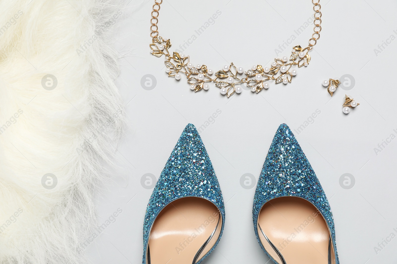 Photo of Fashionable composition with shiny high heeled shoes and accessories on light grey background, flat lay