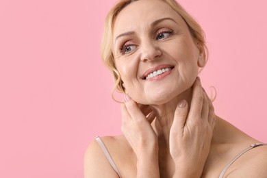 Photo of Smiling middle aged woman on pink background. Space for text