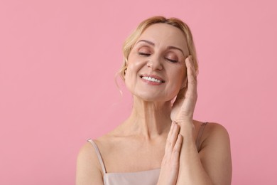 Photo of Smiling middle aged woman on pink background. Space for text