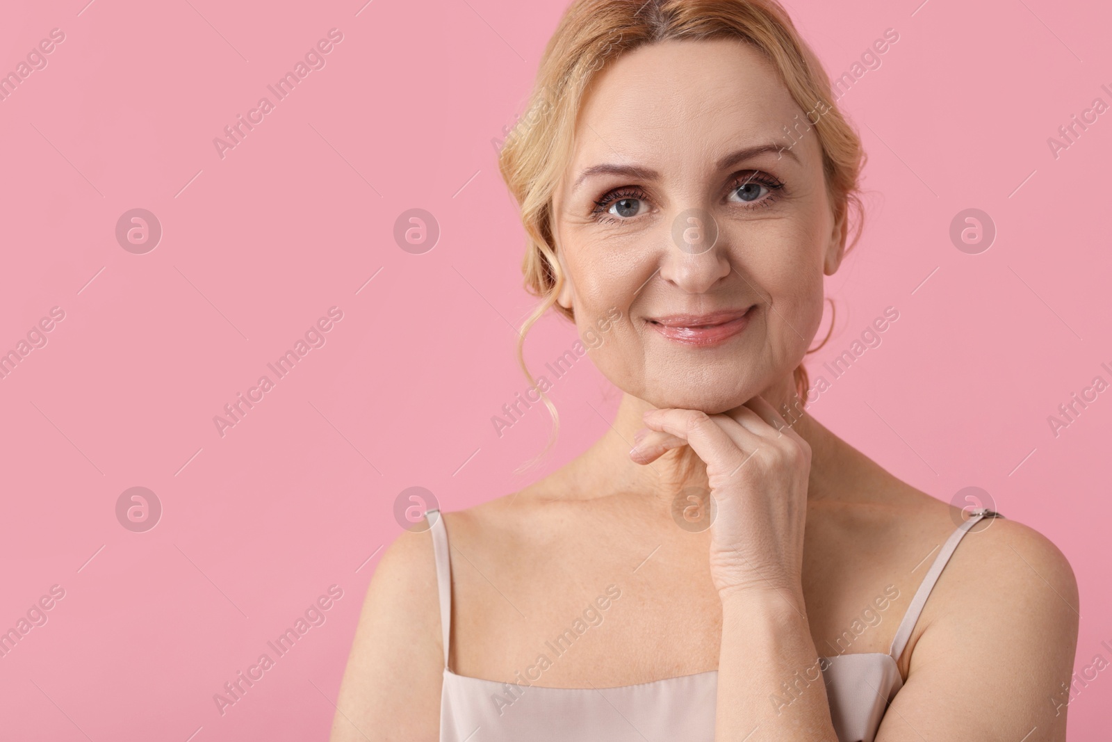 Photo of Portrait of beautiful middle aged woman on pink background. Space for text