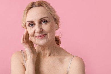 Photo of Portrait of beautiful middle aged woman on pink background. Space for text