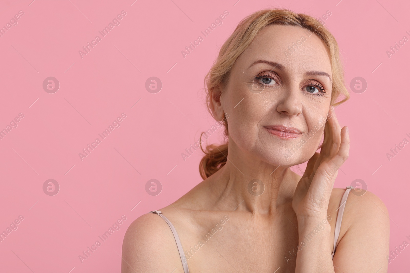 Photo of Portrait of beautiful middle aged woman on pink background. Space for text