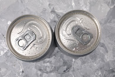 Photo of Refreshing drinks in cans on ice cubes, top view