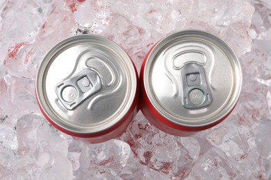 Photo of Refreshing drinks in cans on ice cubes, top view
