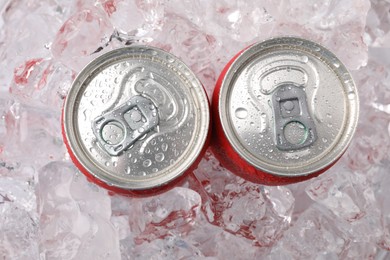 Photo of Refreshing drinks in cans on ice cubes, top view
