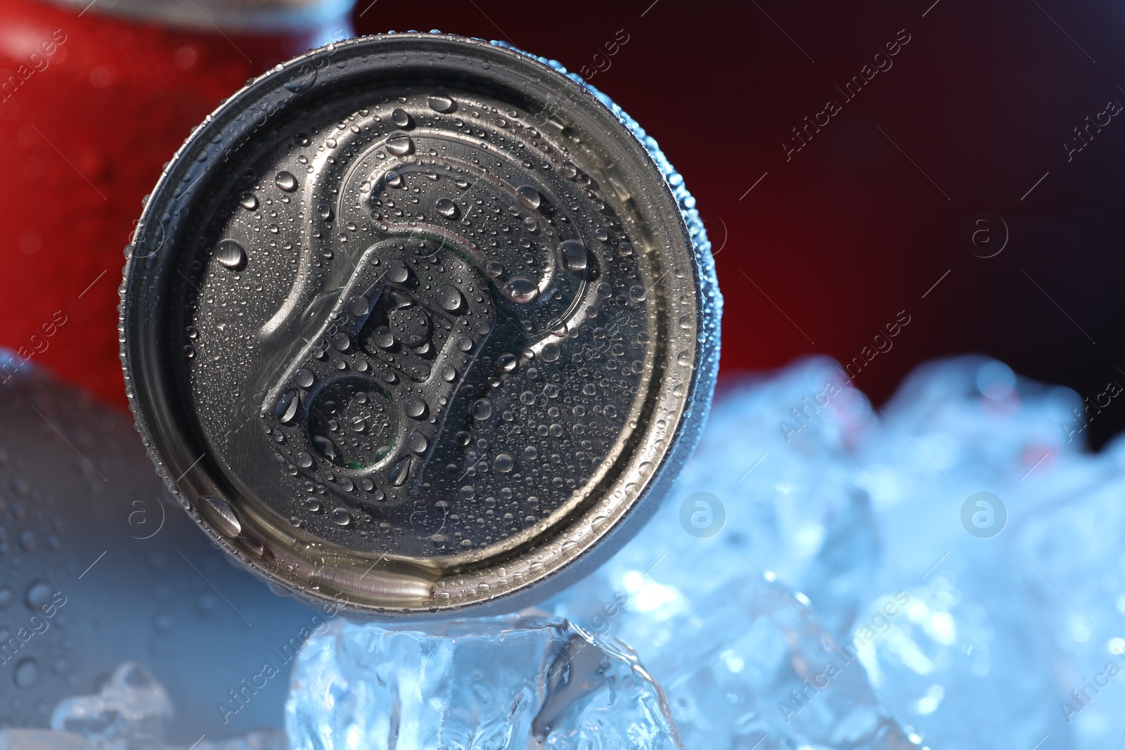 Refreshing drinks in cans on ice cubes against dark red background, closeup. Space for text Photo of Refreshing drinks in cans on ice cubes against dark red background, closeup. Space for text