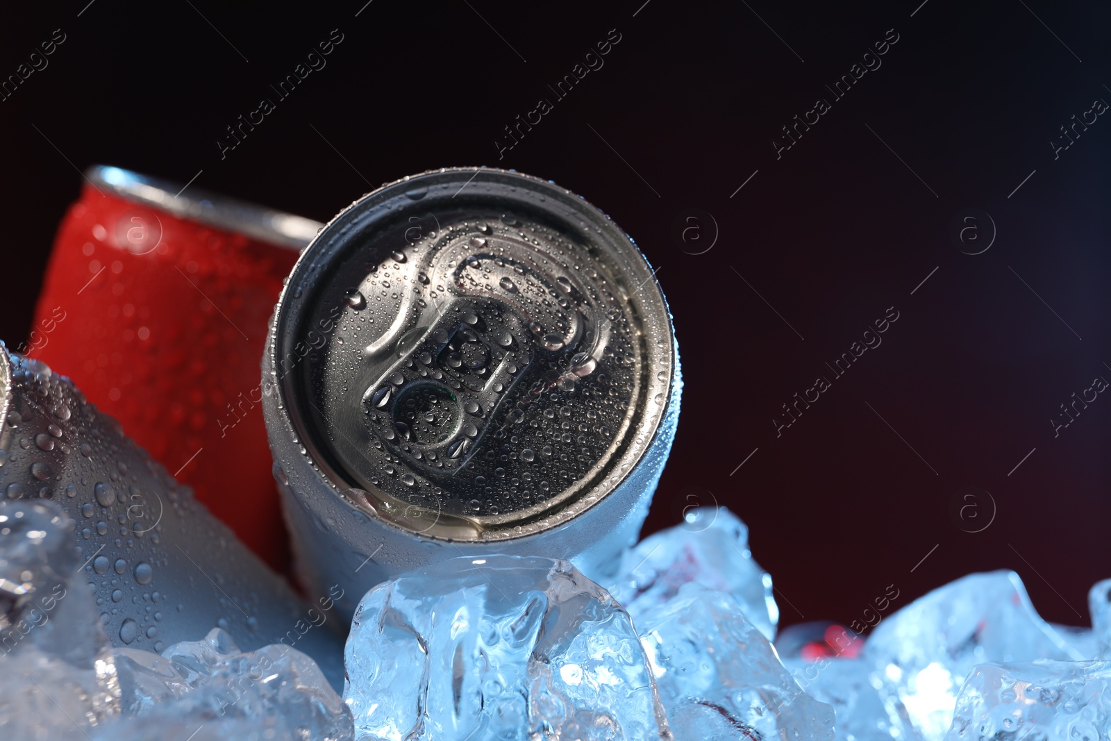 Refreshing drinks in cans on ice cubes against dark background, closeup. Space for text Photo of Refreshing drinks in cans on ice cubes against dark background, closeup. Space for text