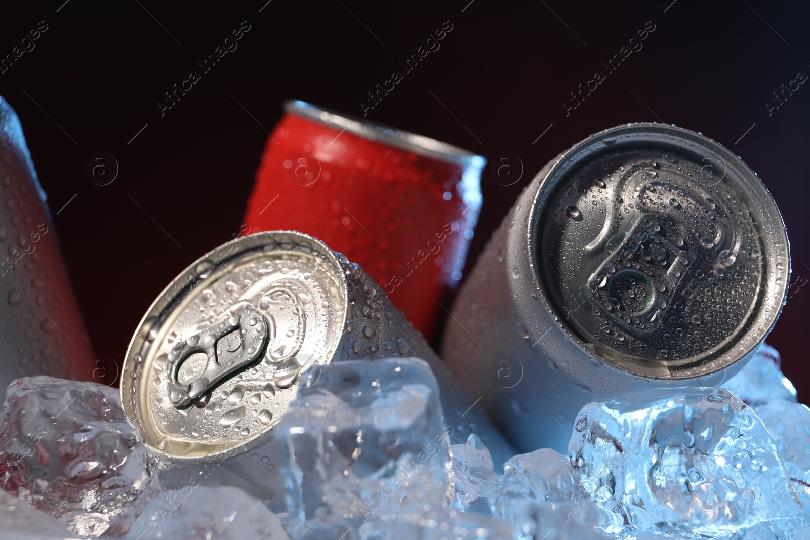 Refreshing drinks in cans on ice cubes against dark background, closeup Photo of Refreshing drinks in cans on ice cubes against dark background, closeup