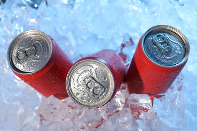 Photo of Refreshing drinks in cans on ice cubes, closeup