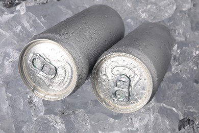 Photo of Refreshing drinks in cans on ice cubes, closeup