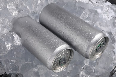 Photo of Refreshing drinks in cans on ice cubes, closeup